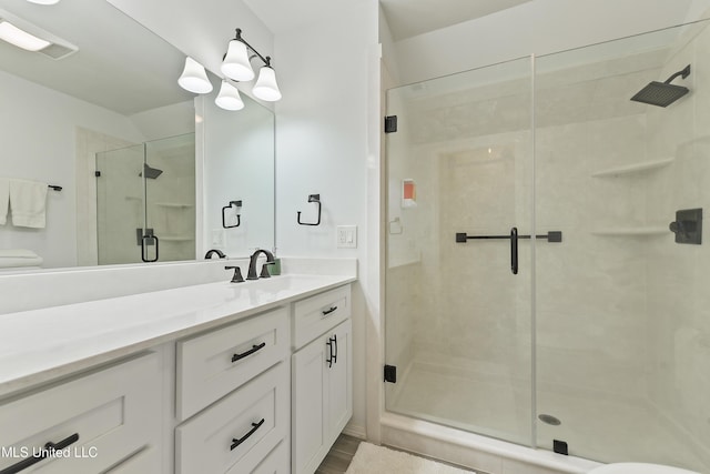 bathroom featuring a shower with shower door and vanity