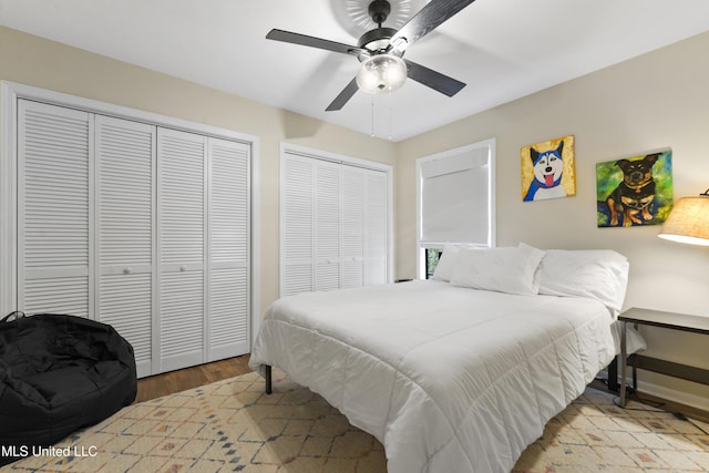 bedroom with ceiling fan, light wood-type flooring, and multiple closets