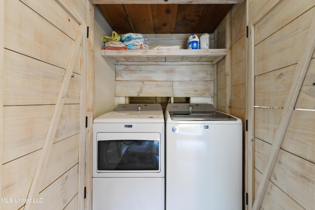 clothes washing area with wood ceiling, wooden walls, and washing machine and dryer