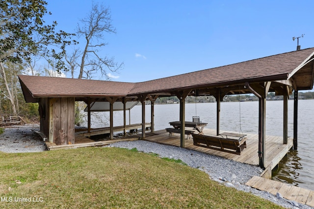 view of dock with a yard and a water view