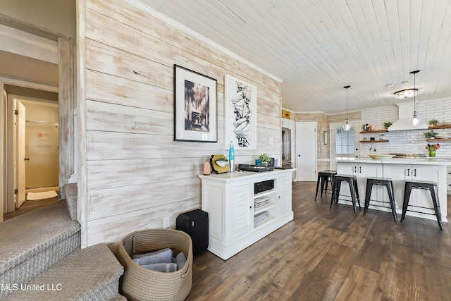 kitchen featuring dark wood-type flooring, decorative light fixtures, a breakfast bar, wood ceiling, and white cabinets