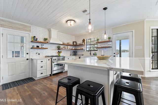 kitchen featuring a breakfast bar area, white cabinetry, premium range hood, and high end stainless steel range