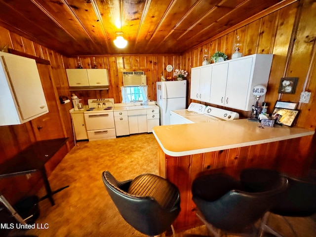 kitchen featuring light countertops, a peninsula, wooden walls, white appliances, and wood ceiling