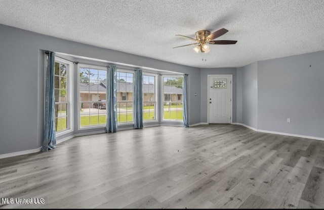 unfurnished room featuring a textured ceiling, light hardwood / wood-style flooring, and ceiling fan