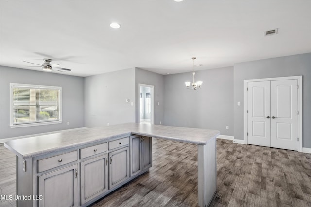 kitchen with a kitchen island, gray cabinetry, dark wood-type flooring, and pendant lighting