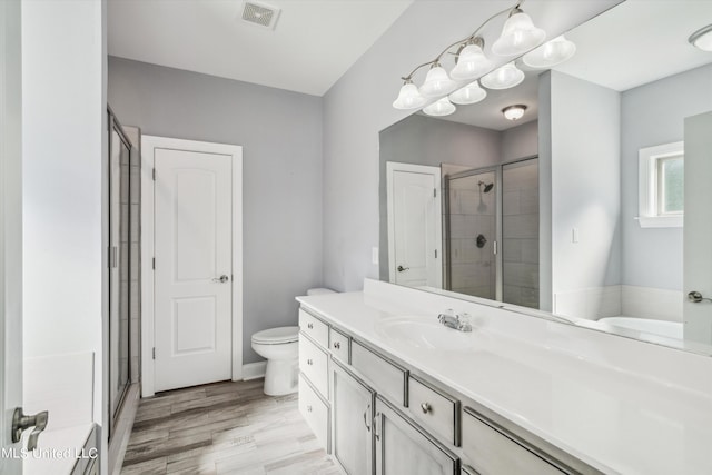 46 Tyro Rd, Holly Springs, MS 38635 - bathroom featuring wood finished floors, toilet, vanity, visible vents, and a stall shower