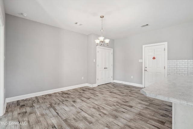46 Tyro Rd, Holly Springs, MS 38635 - unfurnished dining area with a notable chandelier, visible vents, wood finished floors, and baseboards