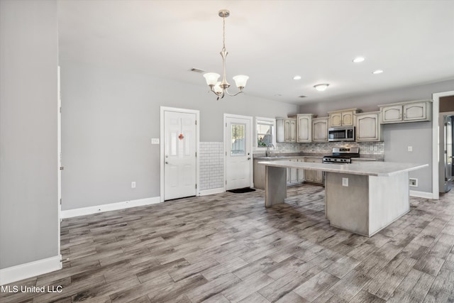 46 Tyro Rd, Holly Springs, MS 38635 - kitchen featuring appliances with stainless steel finishes, light countertops, a center island, an inviting chandelier, and light wood finished floors