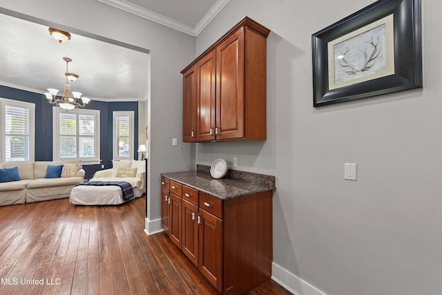 kitchen with dark stone countertops, crown molding, an inviting chandelier, and dark hardwood / wood-style flooring