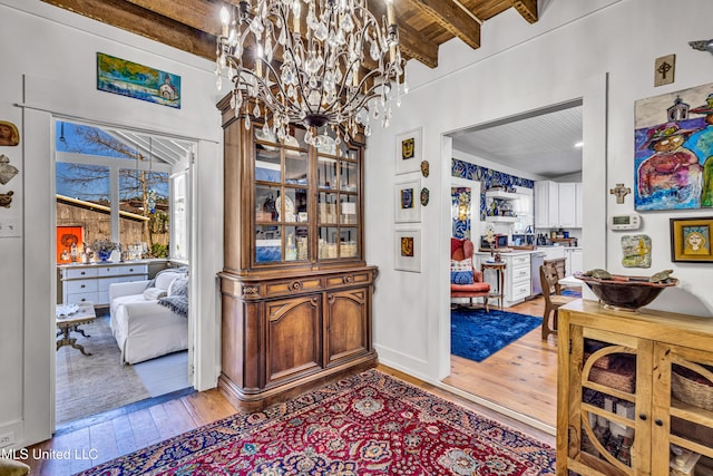 dining space with beam ceiling, light wood-style flooring, and an inviting chandelier