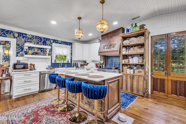 kitchen with premium range hood, light countertops, stainless steel dishwasher, open shelves, and decorative light fixtures