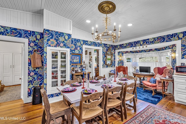 dining room with wallpapered walls, an inviting chandelier, and light wood-style floors