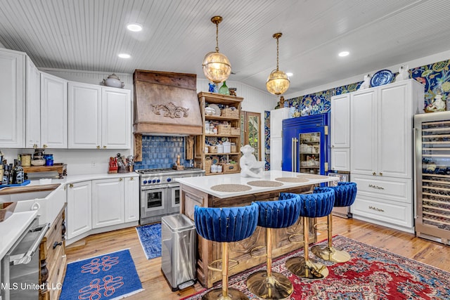 kitchen with premium appliances, beverage cooler, light countertops, custom exhaust hood, and a center island