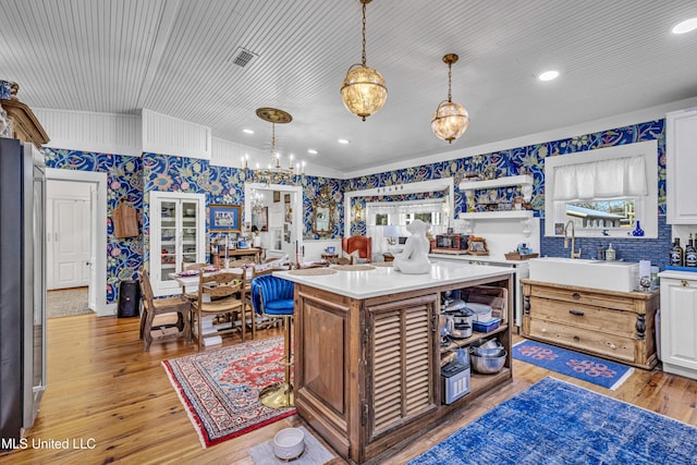 kitchen with light wood-style flooring, a kitchen island, light countertops, open shelves, and a sink