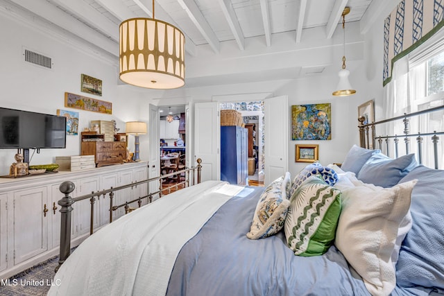 bedroom featuring beamed ceiling, visible vents, and refrigerator