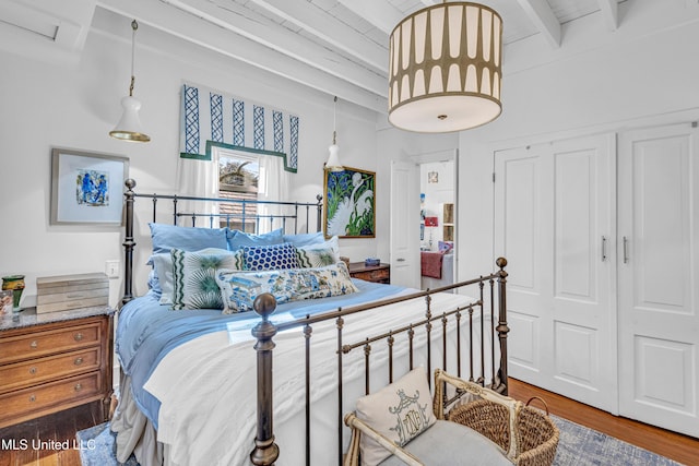 bedroom featuring a closet, dark wood finished floors, and beam ceiling