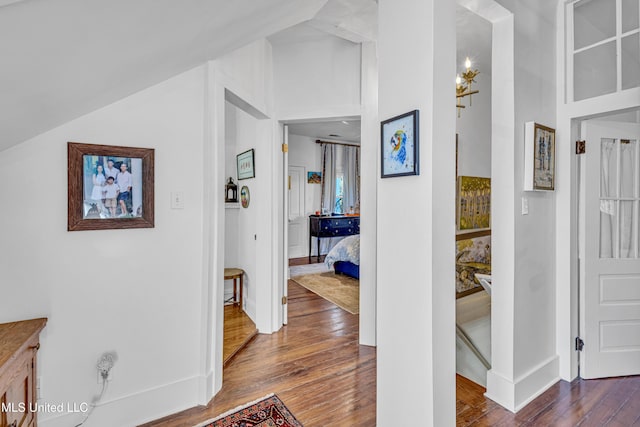 hall with lofted ceiling, baseboards, and wood finished floors