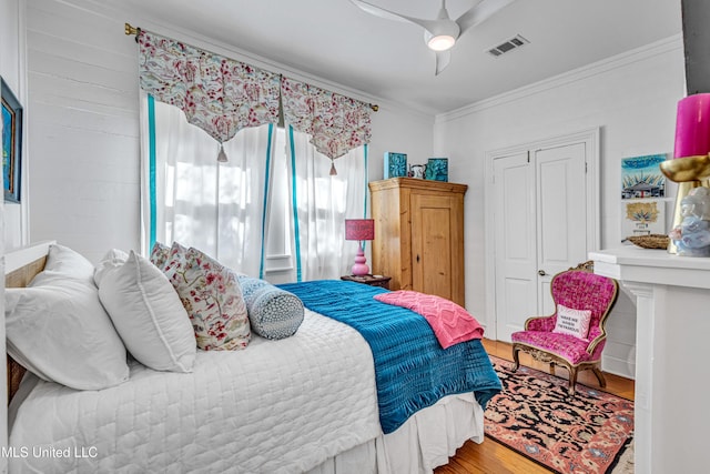 bedroom with ornamental molding, wood finished floors, visible vents, and a ceiling fan