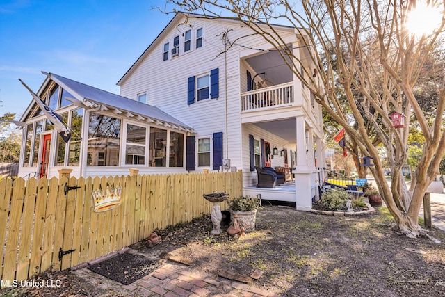 rear view of house with fence and a balcony