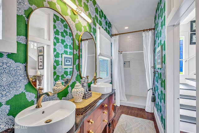 bathroom with a shower with curtain, wallpapered walls, a sink, and wood finished floors