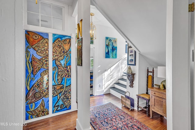 foyer with lofted ceiling, stairway, baseboards, and wood finished floors