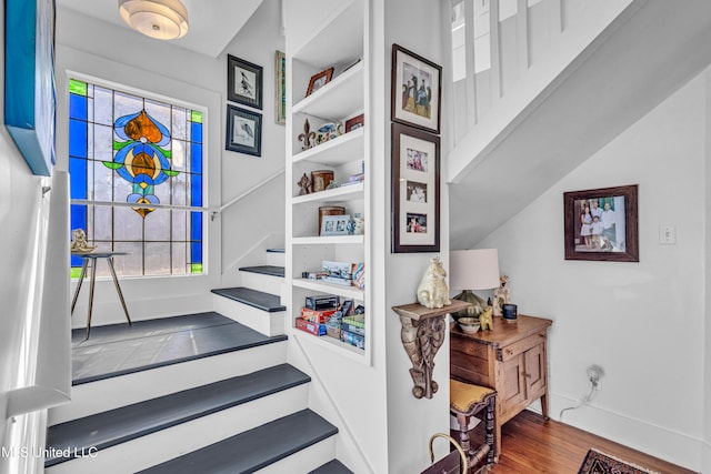 stairs with a wealth of natural light, baseboards, and wood finished floors