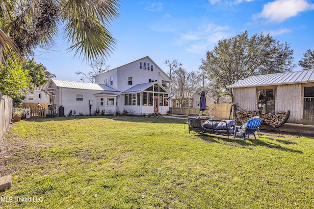 exterior space with metal roof, a yard, a fenced backyard, and a sunroom