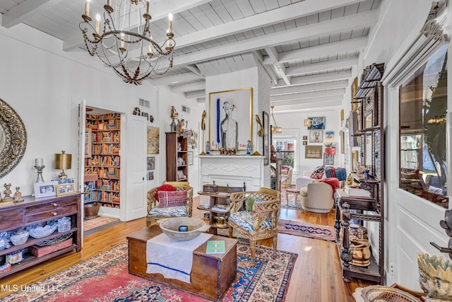 living area featuring beam ceiling, wood finished floors, wood ceiling, and a notable chandelier