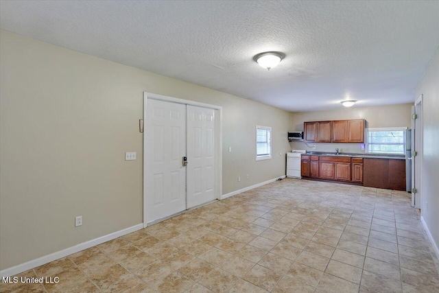 315 Wilson Welch Rd, Mendenhall, MS 39114 - kitchen featuring stove, healthy amount of natural light, a sink, brown cabinetry, and a textured ceiling