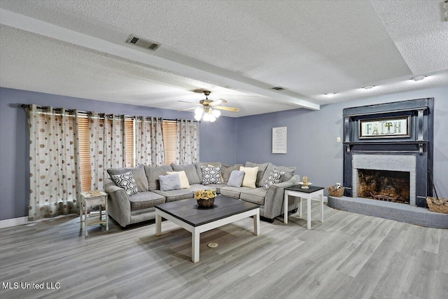 315 Wilson Welch Rd, Mendenhall, MS 39114 - living room featuring a textured ceiling, light wood-style flooring, a brick fireplace, a ceiling fan, and baseboards
