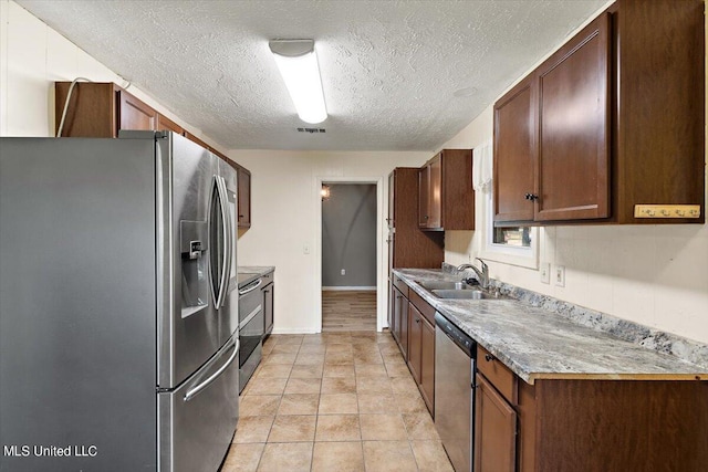 kitchen with sink, stainless steel appliances, a textured ceiling, and light tile patterned floors