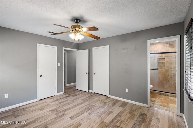 unfurnished bedroom featuring ensuite bathroom, a textured ceiling, light wood-type flooring, and ceiling fan