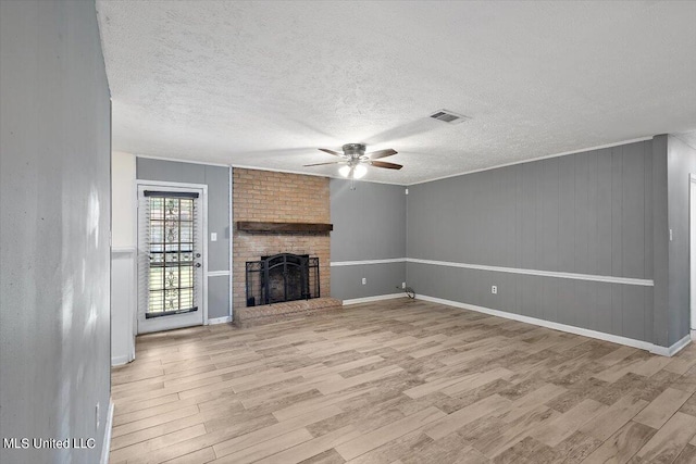 unfurnished living room with a textured ceiling, light wood-type flooring, and a fireplace