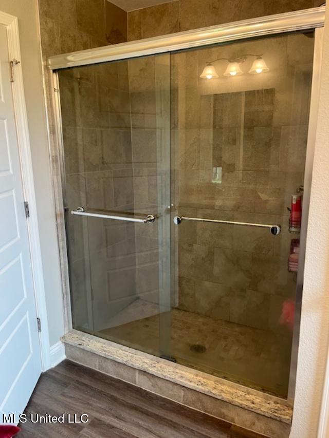 bathroom featuring wood finished floors and a stall shower