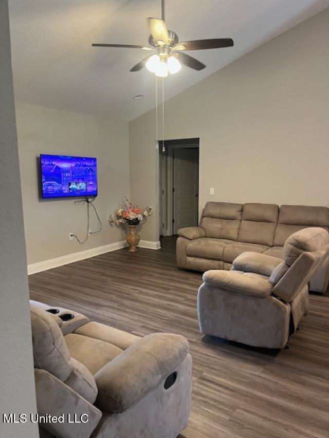 living room with ceiling fan, wood finished floors, vaulted ceiling, and baseboards