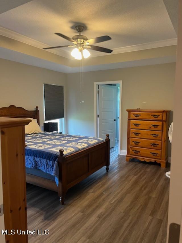 bedroom with dark wood-style floors, crown molding, baseboards, and ceiling fan