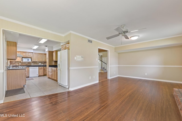 unfurnished living room featuring stairway, light wood-type flooring, a ceiling fan, visible vents, and ornamental molding