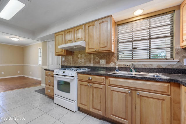 kitchen featuring light tile patterned floors, a sink, plenty of natural light, white range with gas cooktop, and under cabinet range hood