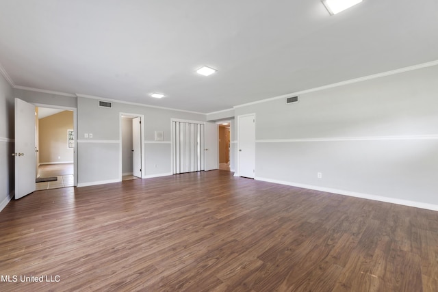 empty room featuring baseboards, visible vents, crown molding, and dark wood-type flooring