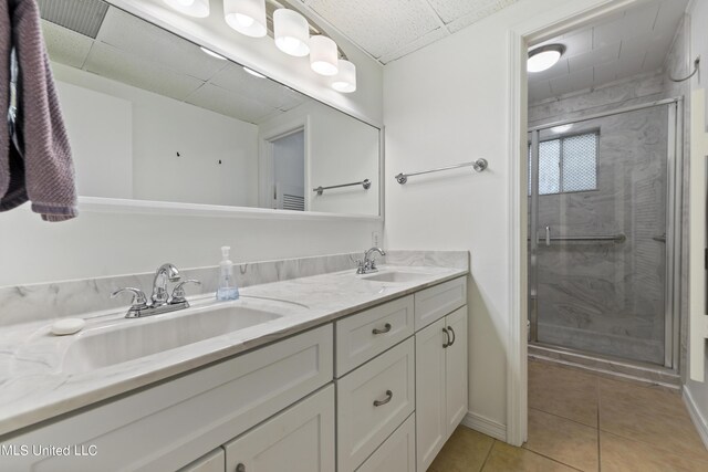 bathroom featuring a stall shower, tile patterned flooring, a sink, and double vanity
