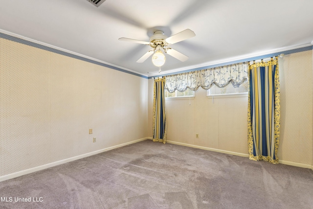 empty room featuring a ceiling fan, carpet floors, and crown molding