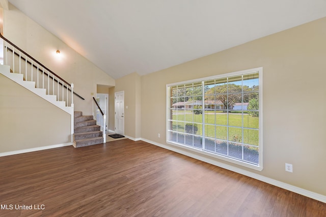 foyer featuring baseboards, stairway, wood finished floors, and lofted ceiling