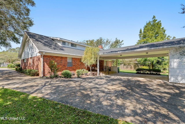 view of front facade with a carport, aphalt driveway, and brick siding