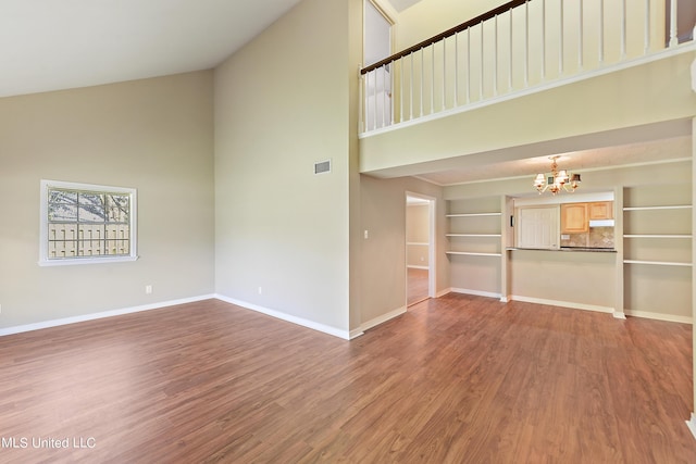 unfurnished living room with visible vents, high vaulted ceiling, wood finished floors, and a notable chandelier