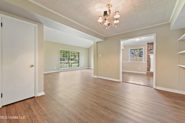 unfurnished dining area with a textured ceiling, a chandelier, vaulted ceiling, light hardwood / wood-style flooring, and ornamental molding