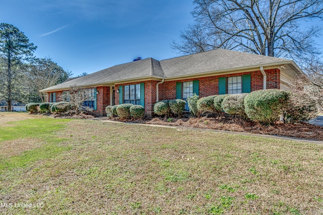 view of front of home with a front yard, brick siding, and roof with shingles