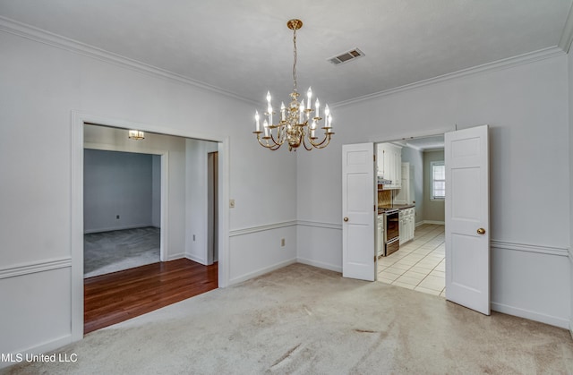 unfurnished room featuring light carpet, baseboards, visible vents, ornamental molding, and a chandelier