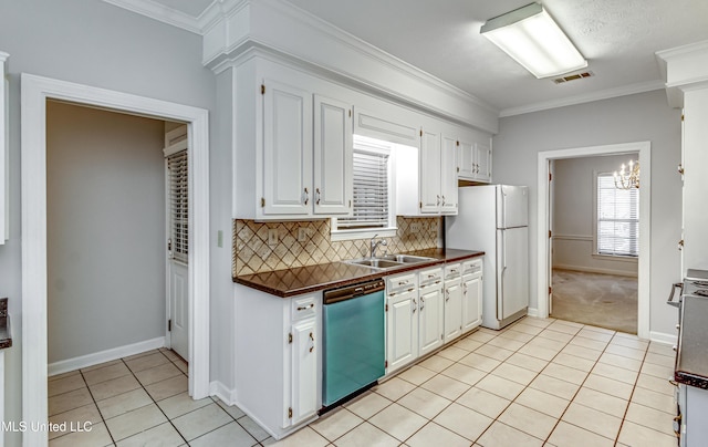 kitchen featuring visible vents, dishwasher, dark countertops, freestanding refrigerator, and a sink