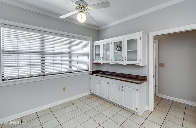 kitchen with crown molding, dark countertops, glass insert cabinets, white cabinetry, and ceiling fan