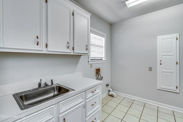 clothes washing area with light tile patterned flooring, washer hookup, a sink, baseboards, and cabinet space